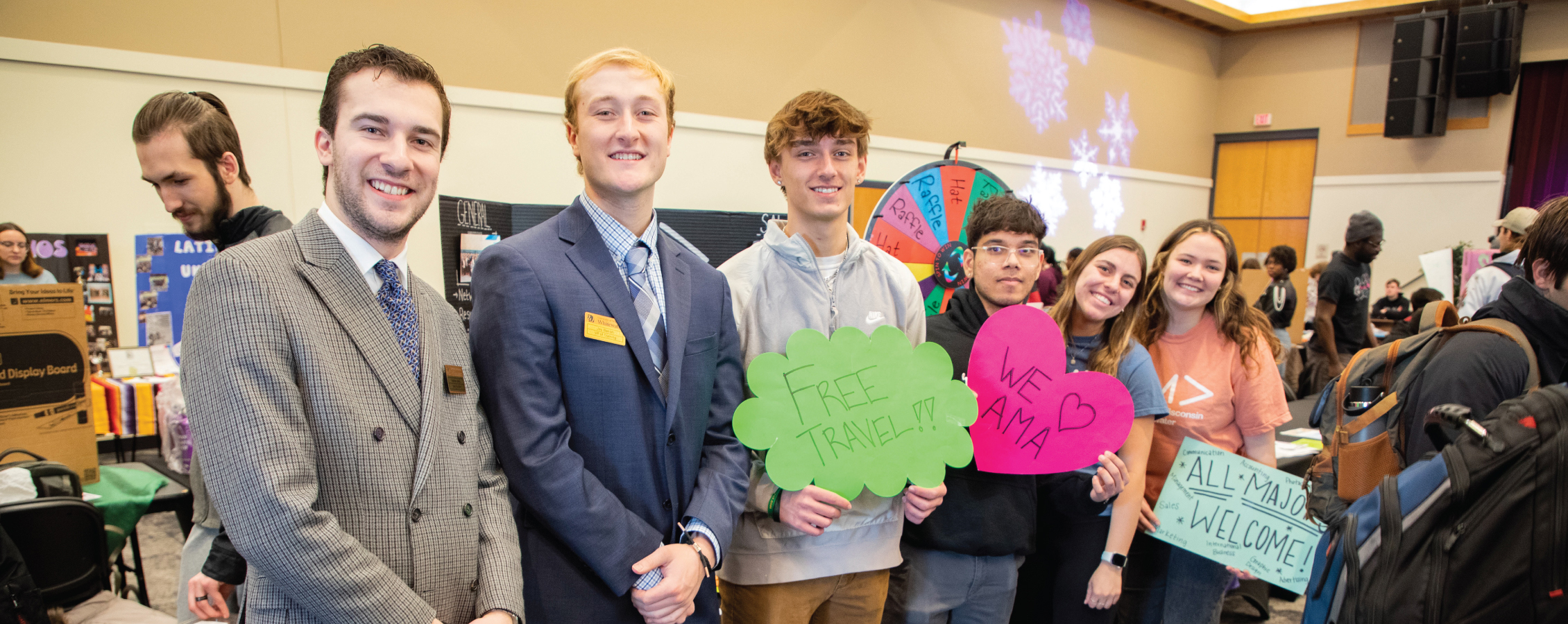 Students stand together in a row and hold colorful signs to represent their organization.